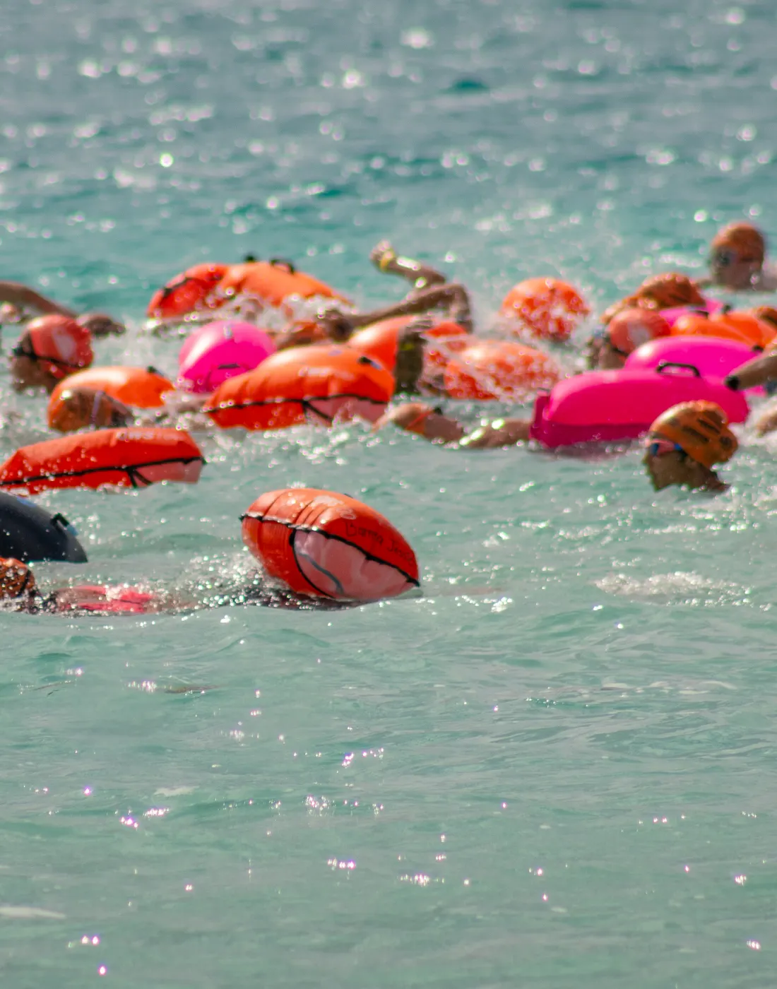 Boyas de seguridad de colores flotando junto a nadadores en la laguna de Bacalar